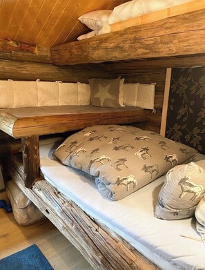 Ein Stockbett mit einem Holzkopfstück und einem gemusterten Kissen.