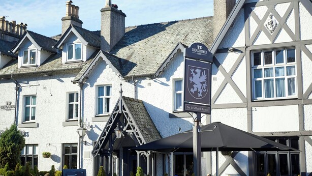 A traditional building with a pub sign, multiple chimneys, and a Tudor-style architectural design.