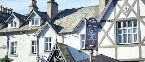 Un edificio tradicional con una señal de pub, múltiples chimeneas y un diseño arquitectónico al estilo Tudor.