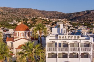 Un hotel llamado KALYPSO con una estructura en forma de cúpula, rodeado de palmeras y un paisaje montañoso.