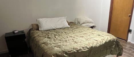 Ein Schlafzimmer mit einem Bett, Kissen, einem Nachttisch und einer Tür.