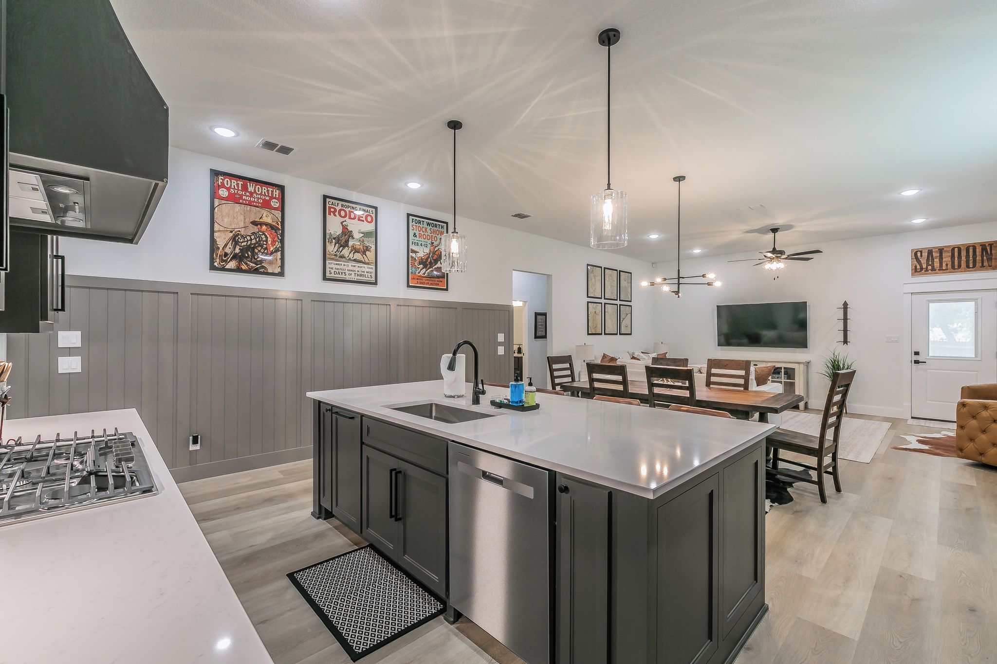 A modern kitchen with a central island, stainless steel appliances, and a dining area with a large TV.