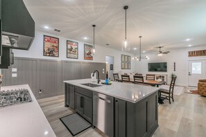 Una cocina moderna con una isla central, electrodomésticos de acero inoxidable y un comedor con un televisor grande.