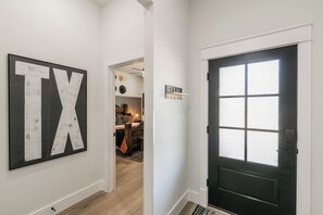 A hallway with a large 'TX' sign, a black door with a window, and a sign reading 'TEXAS'. - 🤠 Welcome to the Stockyards Stable: fire pit, walk to Stockyards & Billy Bob’s! (Fort Worth)