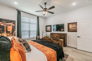 A bedroom with a bed, a ceiling fan, a TV, and a door. - 🤠 Welcome to the Stockyards Stable: fire pit, walk to Stockyards & Billy Bob’s! (Fort Worth)
