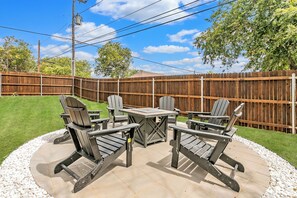 An outdoor patio with a table and chairs, surrounded by a wooden fence and a grassy lawn. - 🤠 Welcome to the Stockyards Stable: fire pit, walk to Stockyards & Billy Bob’s! (Fort Worth)