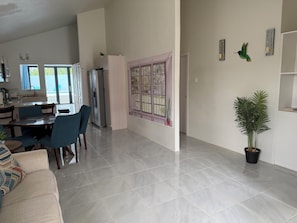 A modern living room with a dining area, a kitchen, and a large window.