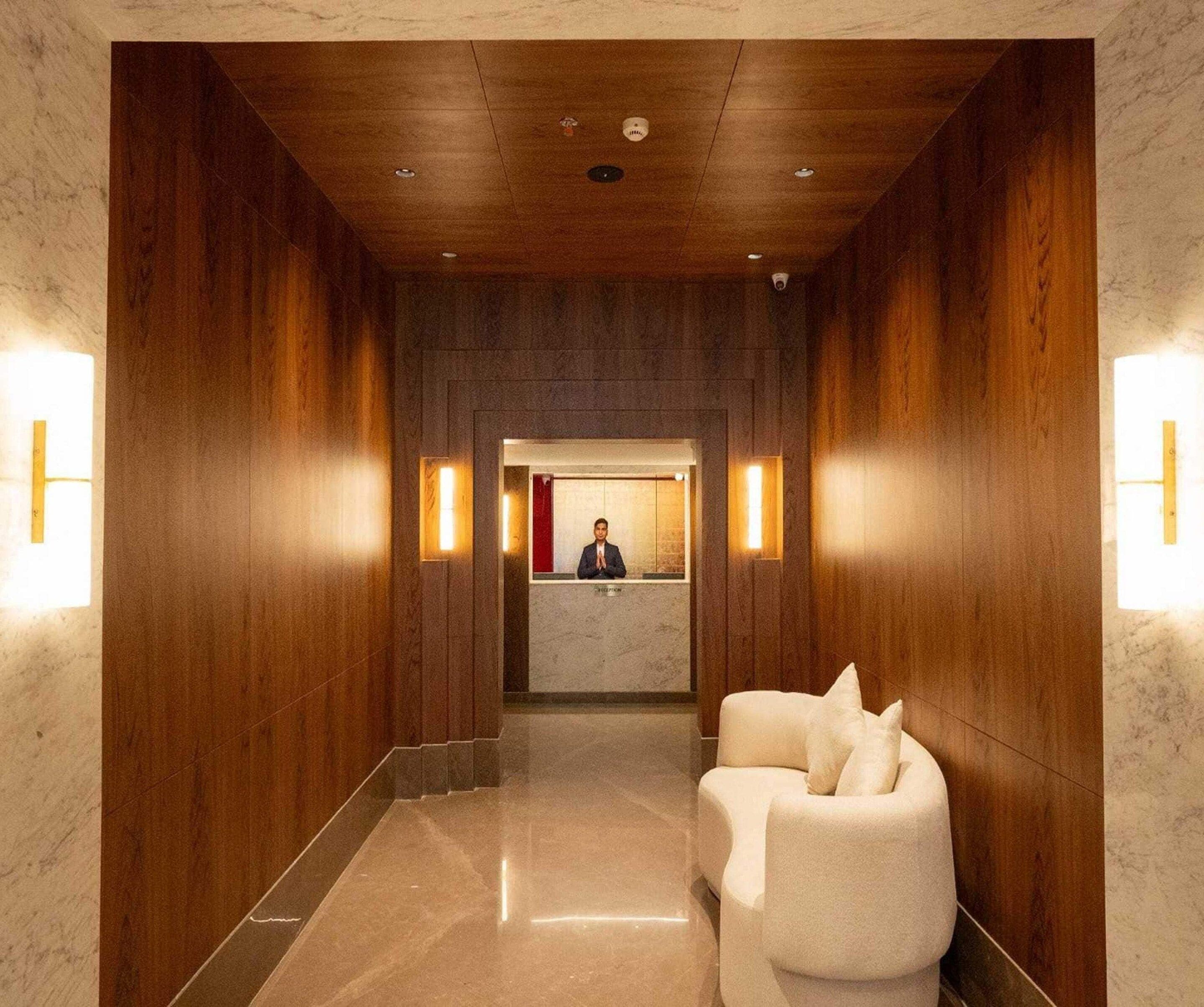 A hotel reception area with a wooden interior, a reception desk, and two white armchairs.
