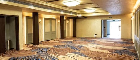 Pasillo de hotel con alfombra estampada, puertas y luces en el techo.