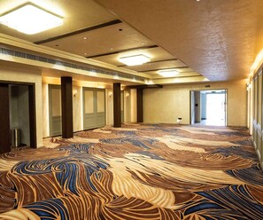 Pasillo de hotel con alfombra estampada, puertas y luces en el techo.