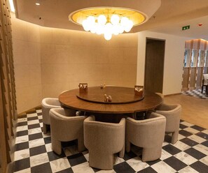 A round table with six chairs, a chandelier, and a checkered floor.