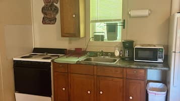 Une cuisine de taille réduite équipée d’une cuisinière, d’un four à micro-ondes, d’un évier et de placards.