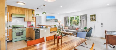 A modern kitchen with wooden cabinets, a built-in oven, and a dining area with a wooden table and chairs.