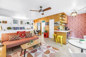 A modern living room with a sofa, coffee table, and a dining area with stools. - Lido Beach House Family Complex (Sarasota)