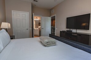A hotel room with a bed, a TV, a desk, and a bathroom visible through an open door. - Vista Cay 3BR near Universal & Convention (Orlando)