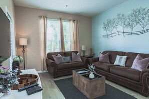 A living room with two brown sofas, a coffee table, a globe, and a wall art piece. - Vista Cay 3BR near Universal & Convention (Orlando)