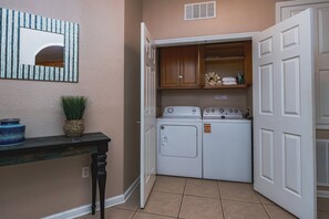 A laundry room with a washing machine, dryer, and a cabinet with towels. - Vista Cay 3BR near Universal & Convention (Orlando)