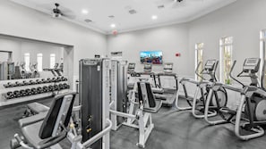 A gym with various exercise machines, dumbbells, and a large mirror. - Vista Cay 3BR near Universal & Convention (Orlando)