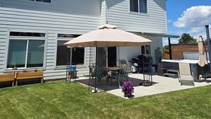 Et toetagers hus med en patio, hvor der står et bord og stole under en stor parasol.
