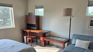 Et værelse med to senge, et skrivebord, en stol, en lampe og en sofa.