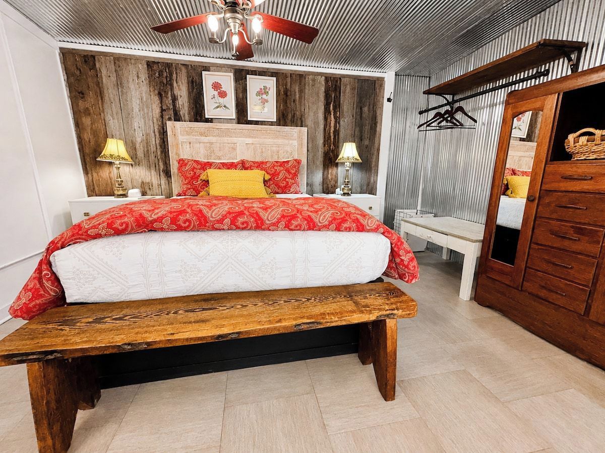 A bedroom with a wooden bed, a bench, a wardrobe, and a ceiling fan.