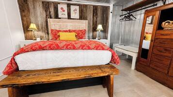 A bedroom with a wooden bed, a bench, a wardrobe, and a ceiling fan.
