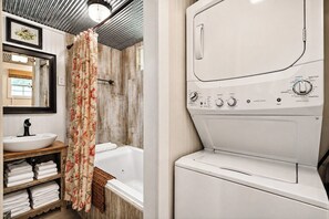 Un baño con un lavabo blanco, una bañera y una lavadora blanca.