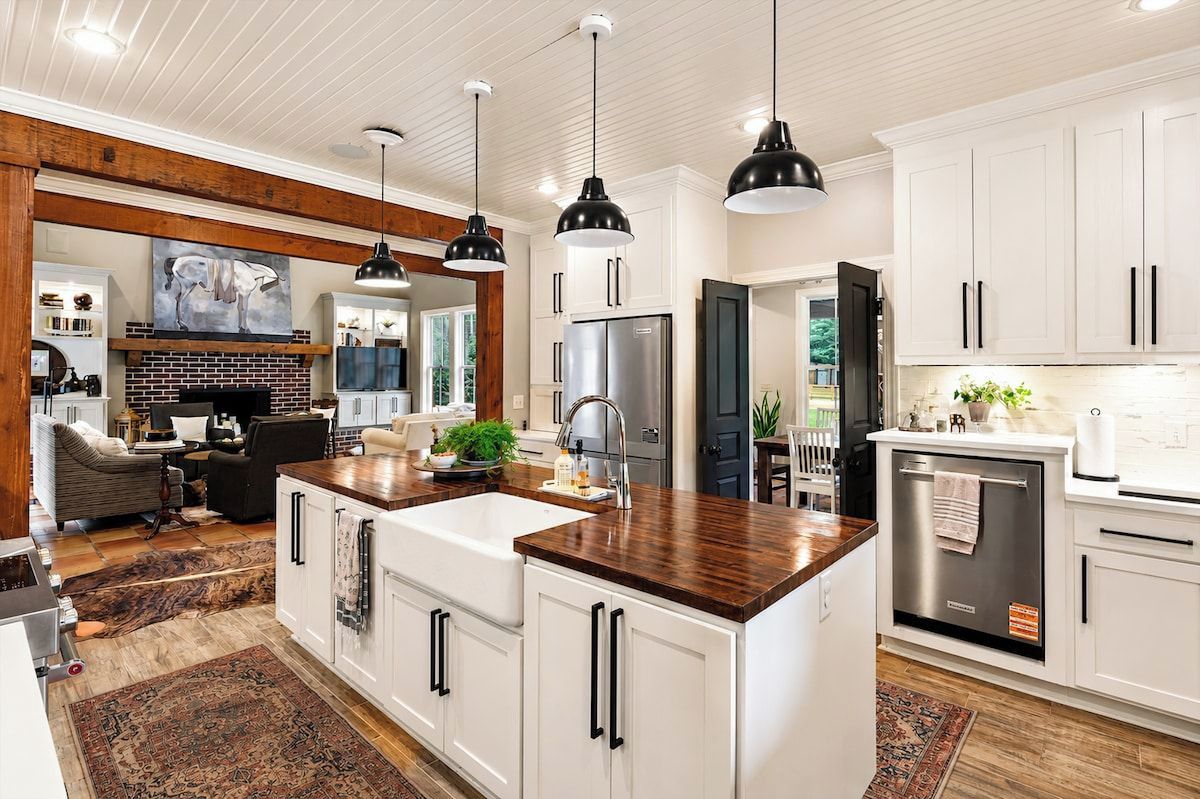 Une cuisine moderne avec des meubles blancs, un îlot central et des luminaires suspendus.