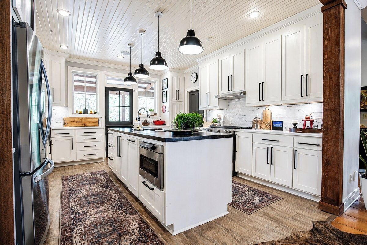 A modern kitchen with white cabinetry, a central island, pendant lighting, and a large refrigerator.