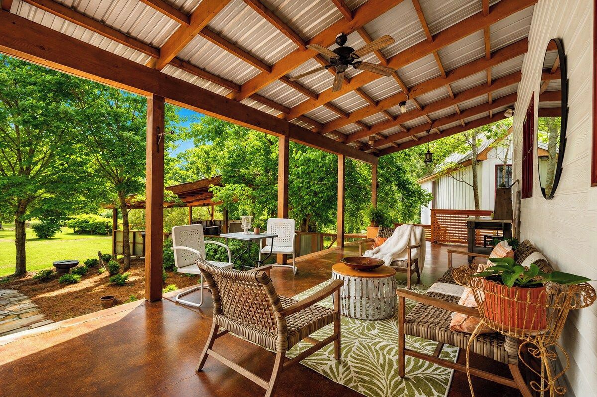 An outdoor patio with wooden furniture, a ceiling fan, and a view of a lush garden.