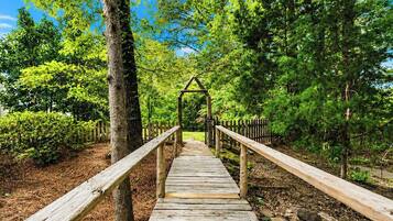 A wooden pathway leading through a forested area with a simple wooden structure at the end.