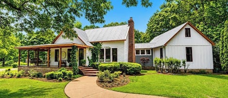 A two-story house with a covered porch, a brick chimney, and a well-maintained lawn.