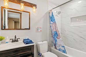 A bathroom with a shower, a sink with a mirror, and a toilet.