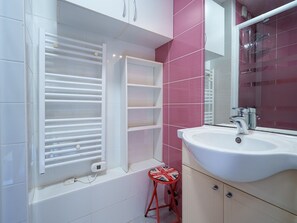 A bathroom with a white sink, a mirror, a red stool, and a window with blinds. - Seaside Apartment in Cap D'agde (Agde)