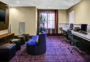 A hotel room with a seating area, a desk with a computer, and a large window with curtains. - Courtyard by Marriott Kansas City Country Club Plaza (Kansas City)