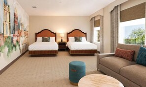 Ein Hotelzimmer mit zwei Betten, einer Couch, einem runden Tisch und einem großen Fenster.