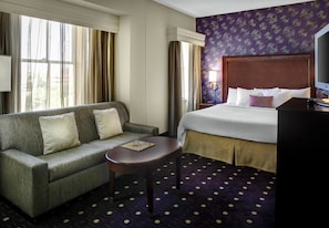 A hotel room with a sofa, a small table, a bed, and a television. - Courtyard by Marriott Kansas City Country Club Plaza (Kansas City)