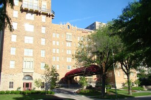 A multi-story hotel with a brick facade, a covered entrance, and a clear sky. - Courtyard by Marriott Kansas City Country Club Plaza (Kansas City)