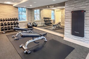 Uma academia com equipamentos de musculação, bolas de exercício e halteres.