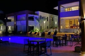 Ein modernes Gebäude mit Pool und Außenbereich zum Sitzen bei Nacht.