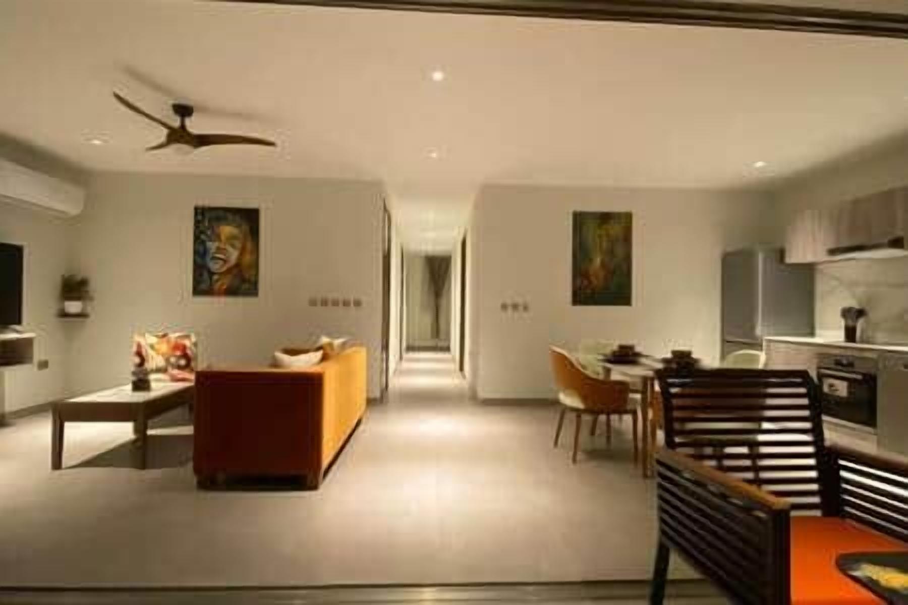 Una sala de estar moderna con un sofá, un comedor con sillas y una cocina al fondo.