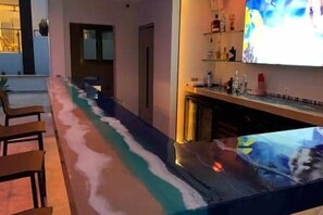 A bar area with a long counter, chairs, and a television screen. - C12-Xanadu Blue Bay Sleeps 4 (Sint Michiel)