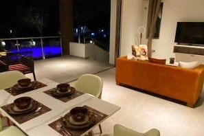 A modern living room with a dining area, a sofa, and a television. - C12-Xanadu Blue Bay Sleeps 4 (Sint Michiel)