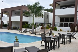 A poolside area with lounge chairs, a small table, and a covered seating area. - B6-Xanadu Blue Bay Sleeps 4 (Sint Michiel)