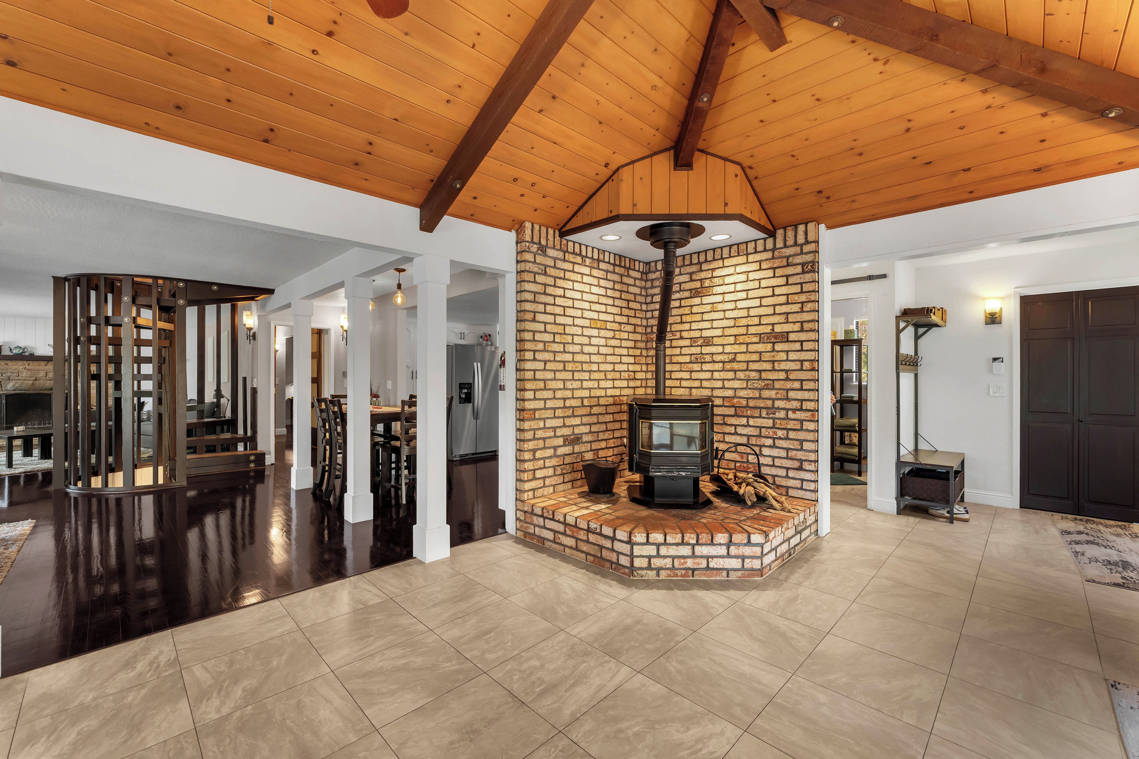 A spacious living area with a fireplace, wooden ceiling beams, and a brick accent wall.