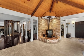A spacious living area with a fireplace, wooden ceiling beams, and a brick accent wall. - Spacious 3-bedroom house in tranquil Lakehead unobstructed lake views (Lakehead)