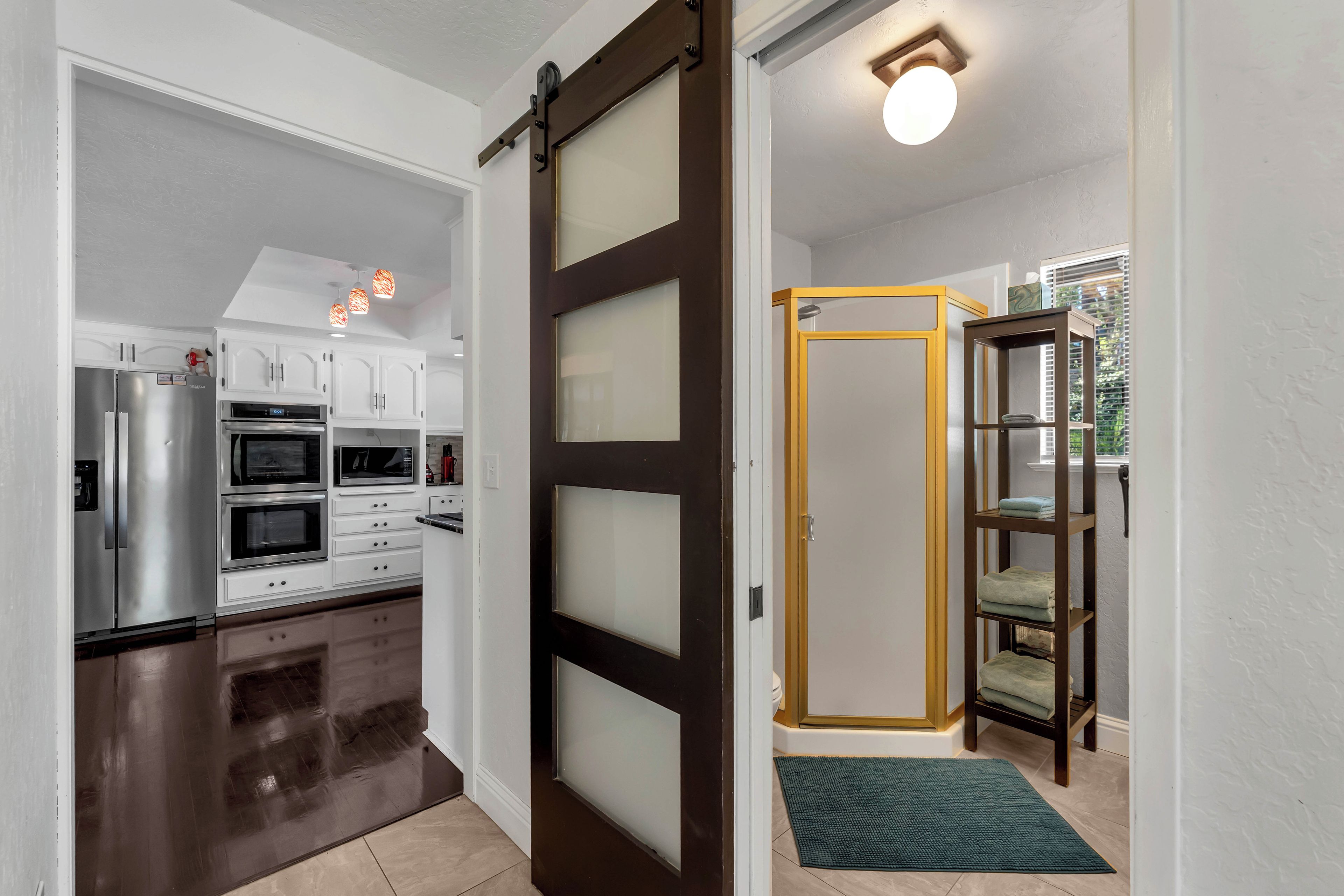 Una cocina moderna con electrodomésticos de acero inoxidable, una puerta corrediza de vidrio y piso de madera.