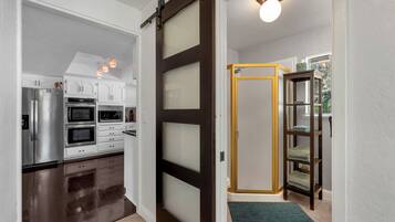 Una cocina moderna con electrodomésticos de acero inoxidable, una puerta corrediza de vidrio y piso de madera.