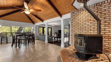 A spacious living area with a fireplace, wooden ceiling, and large windows.