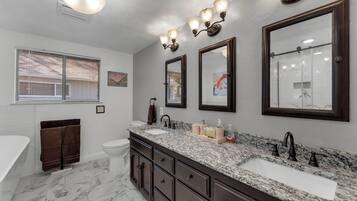 Une salle de bain comprenant un grand meuble-lavabo, une baignoire, des toilettes et un espace douche.